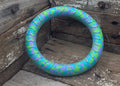 A circular fitness ring with a blue, green, and purple snake-like pattern, resting on a rustic wooden surface.
