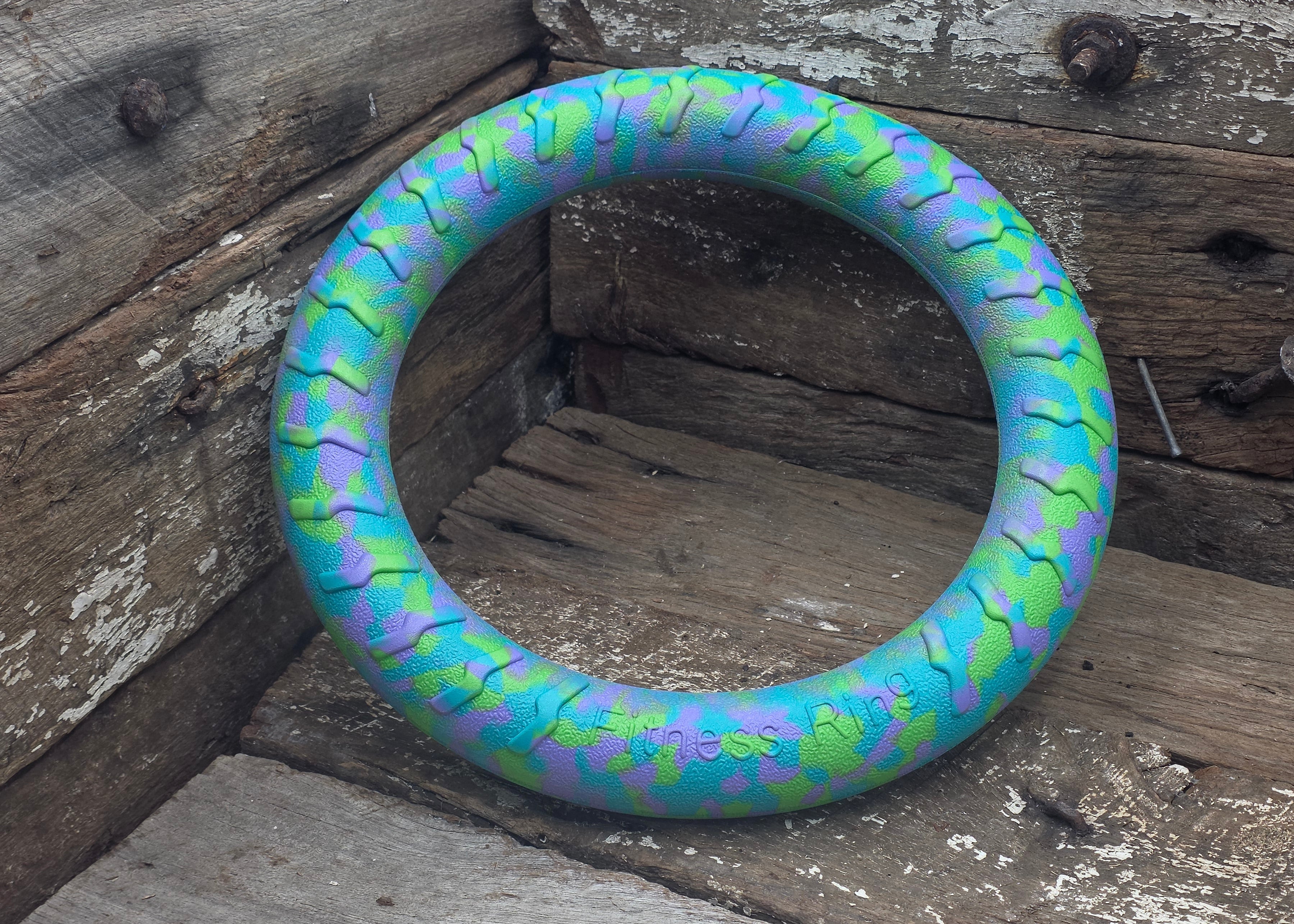 A circular fitness ring with a blue, green, and purple snake-like pattern, resting on a rustic wooden surface.