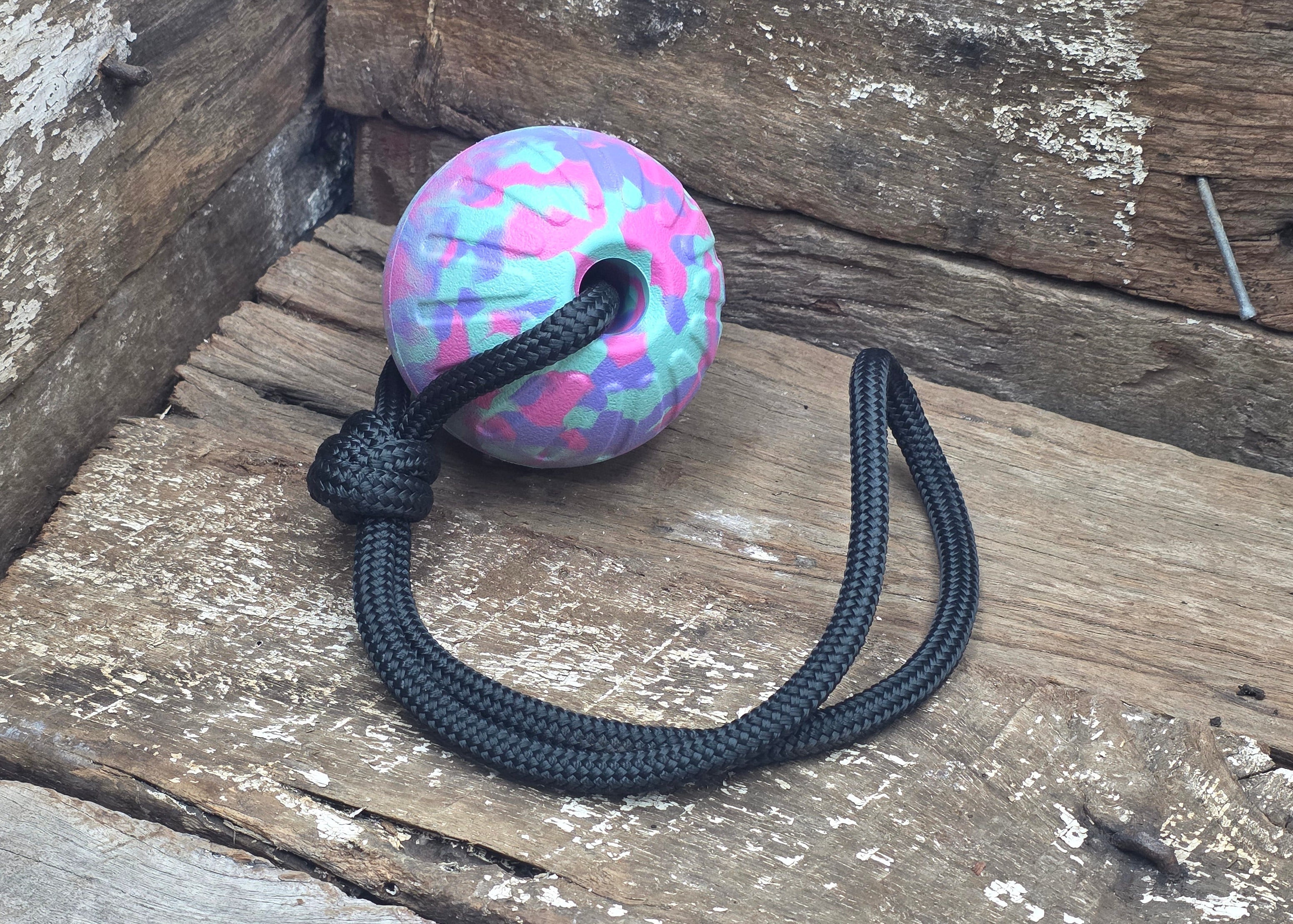 Colorful ball with a black rope on a wooden surface